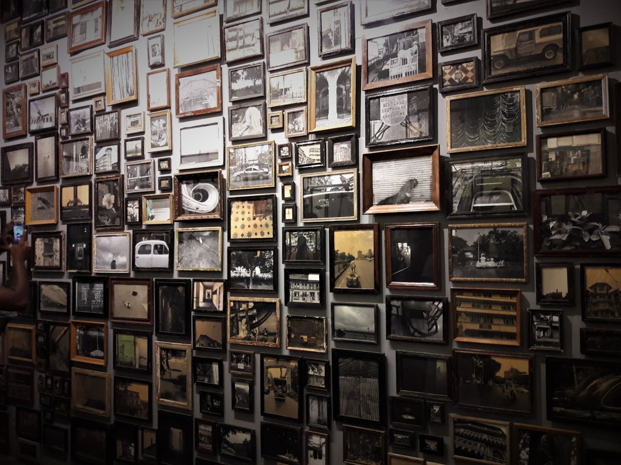 A diverse collection of framed photographs displayed on a gallery wall in Kochi, India.