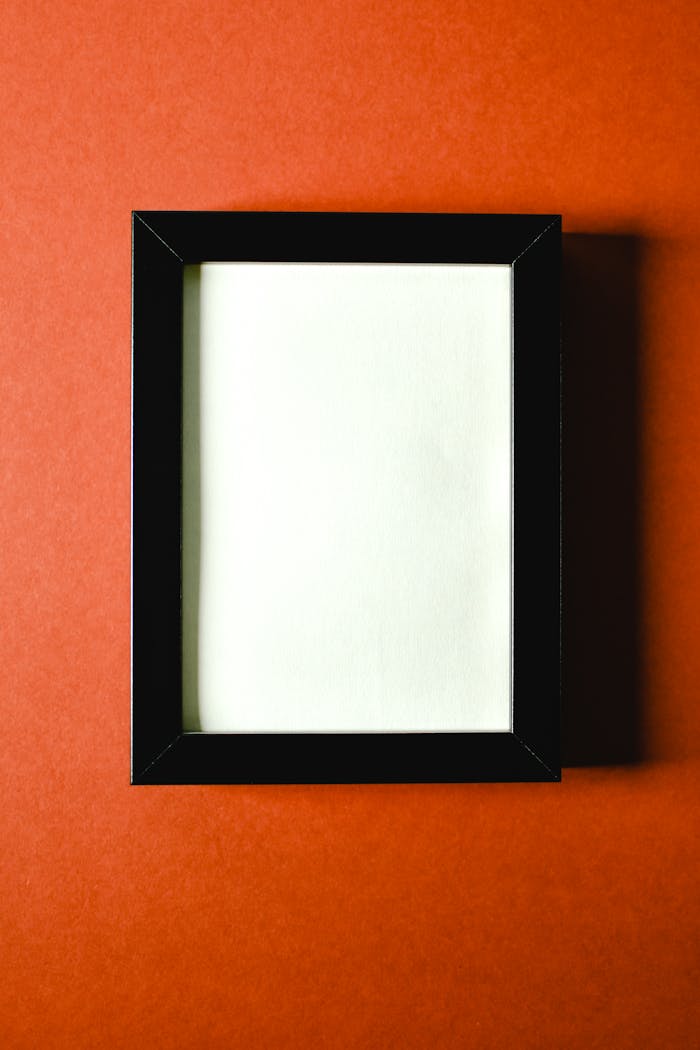 A blank black photo frame displayed on a vibrant red background, perfect for mockups.